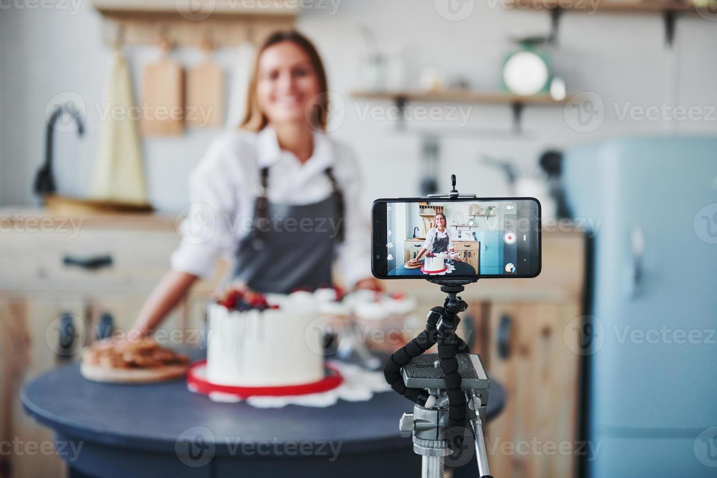 Woman makes delicious sweets and pie. Recording process by smartphone on tripod photo