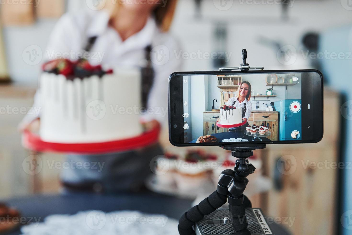 Woman makes delicious sweets and pie. Recording process by smartphone on tripod photo