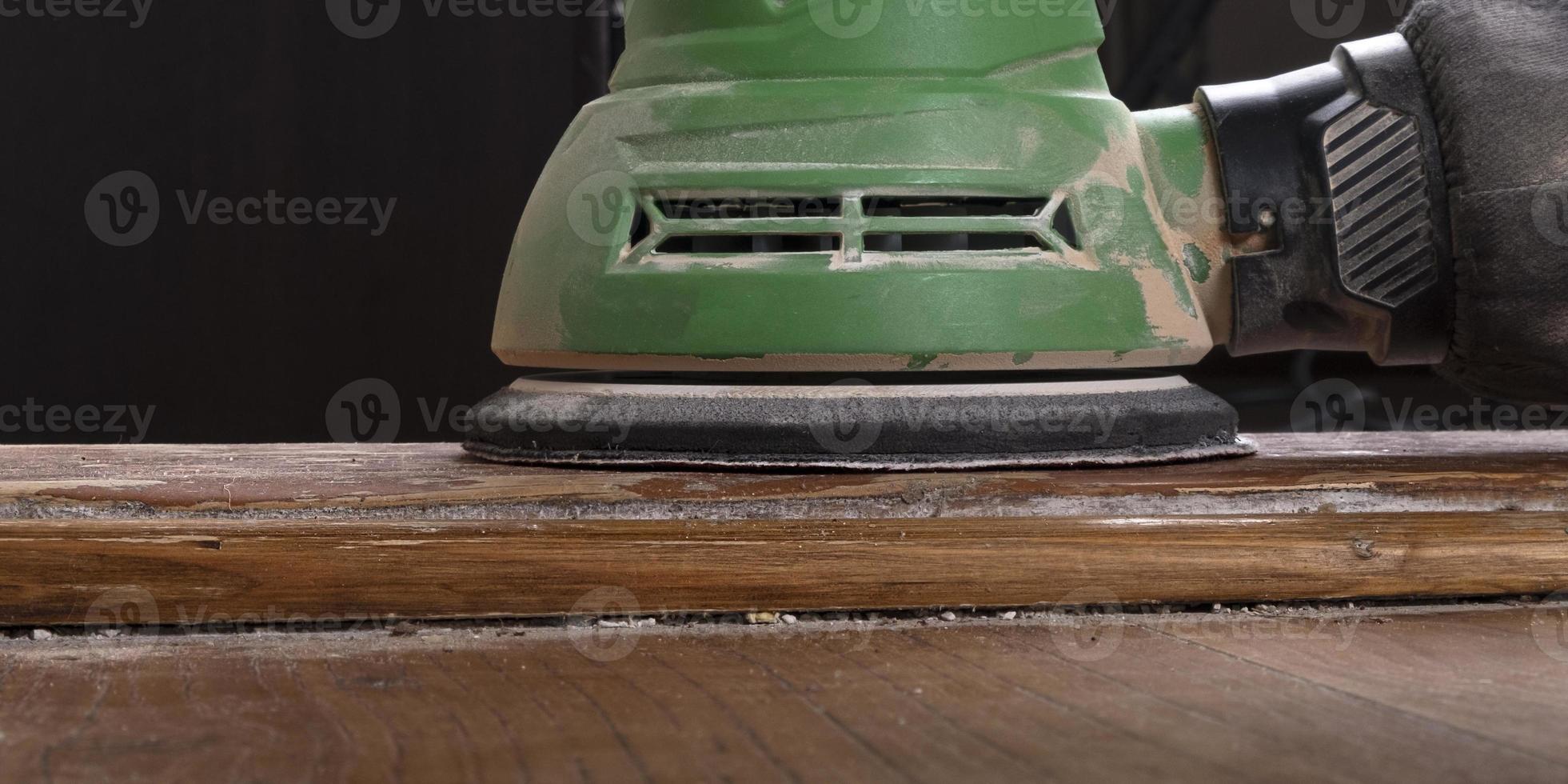 carpenter hand sanding a wooden door furniture with a grinder photo
