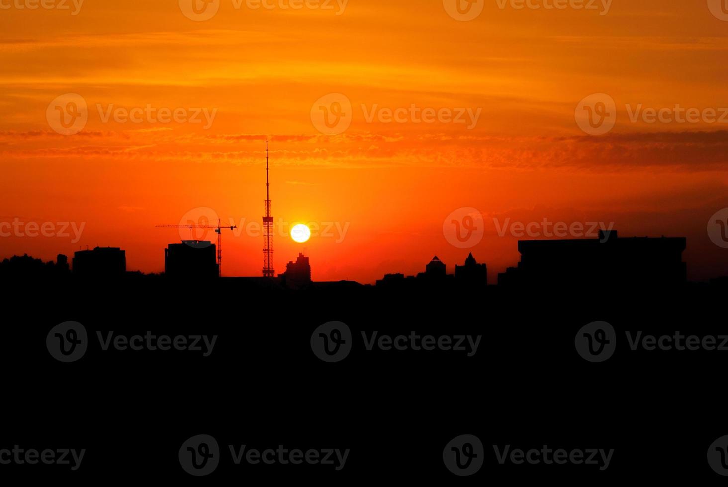 Kyiv TV Tower. Dark silhouette of black buildings and television tower with colorful vibrant orange yellow sunset sun. Ukraine, Kyiv photo