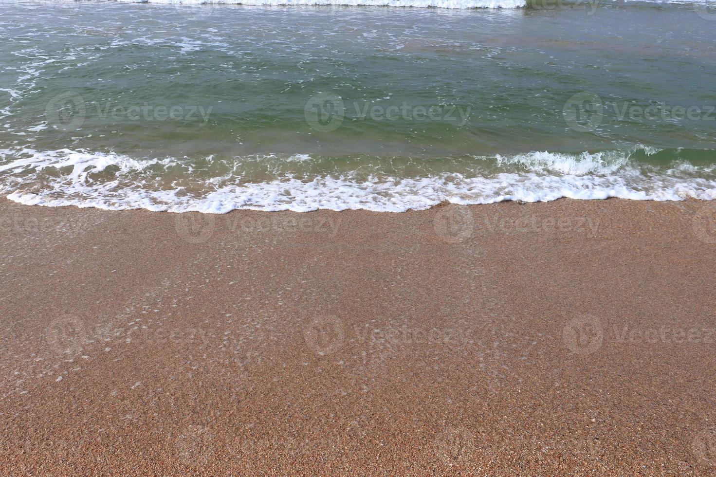 orilla del océano con playa de arena y olas que avanzan foto