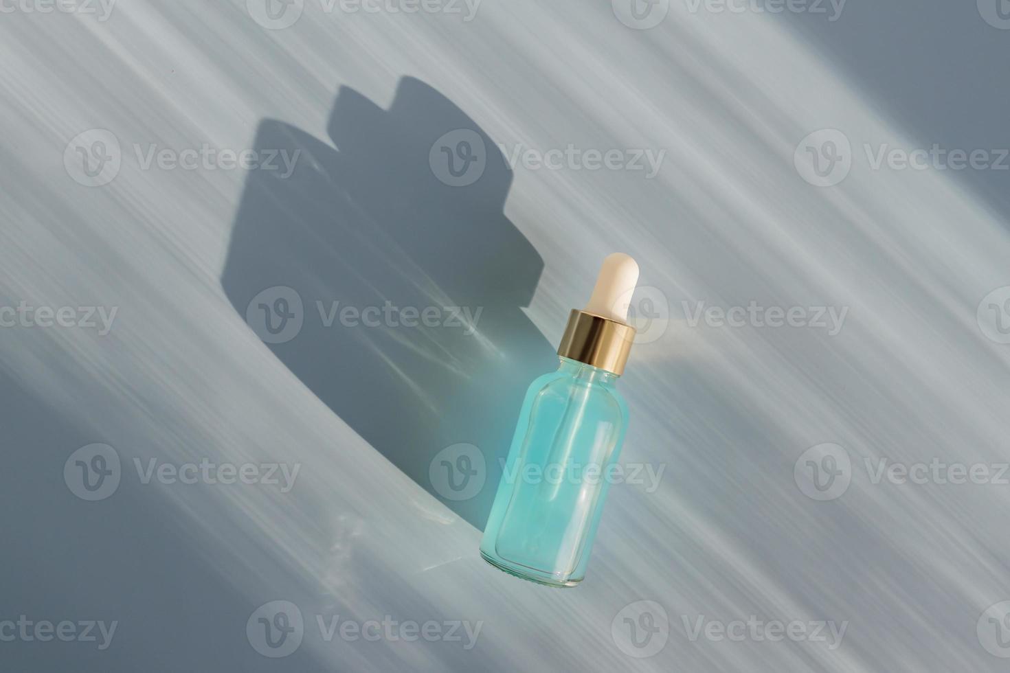 Cosmetic spa medical skincare, glass serum bottle with collagen on blue background with shadows. medical product adverticement for anti-aging care with marine ingredients photo