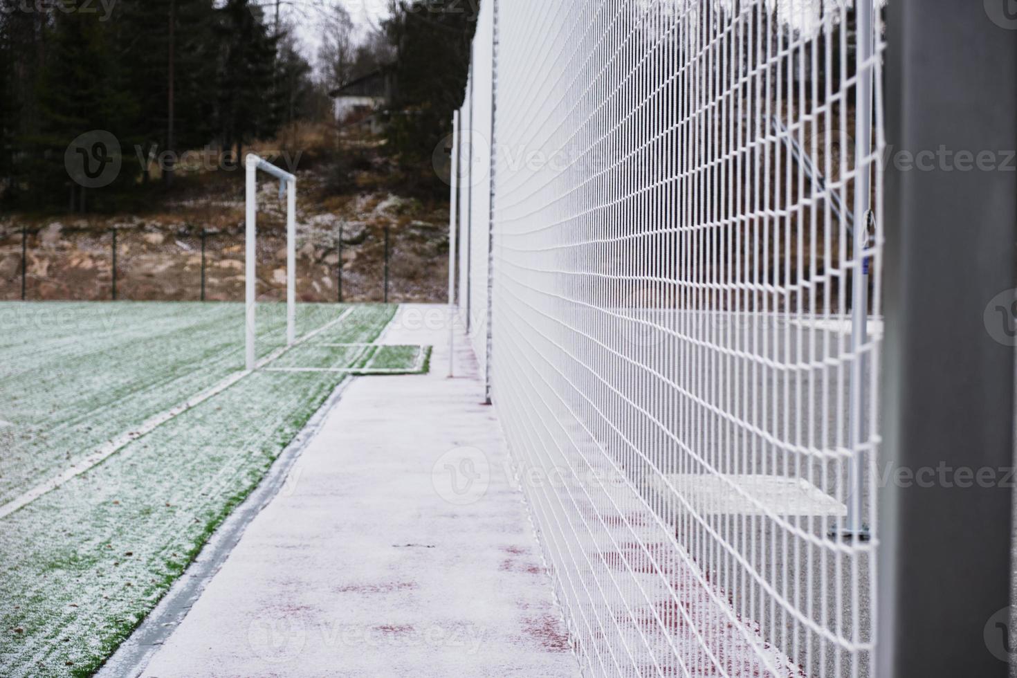 football field, lawn under snow, first snow on grass, football field markings, net on the sports field photo