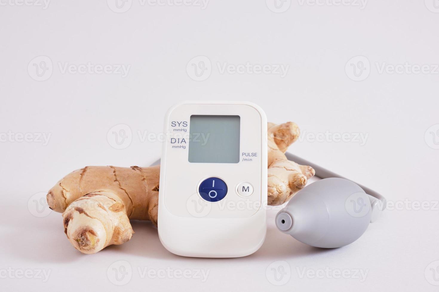 blood pressure monitor and ginger root on gray background photo