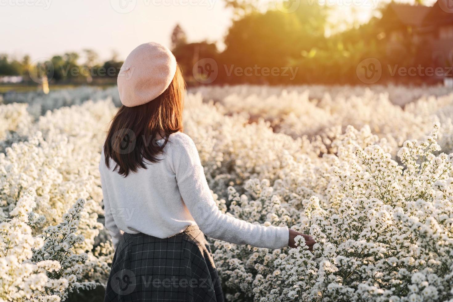 mujer joven caminando y disfrutando en un campo de flores blancas foto