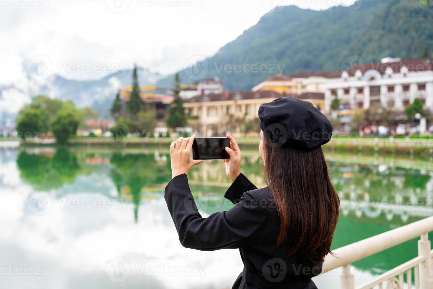 mujer joven tomando una foto en el lago sapa con reflejo y cielo azul en la provincia de lao cai, vietnam