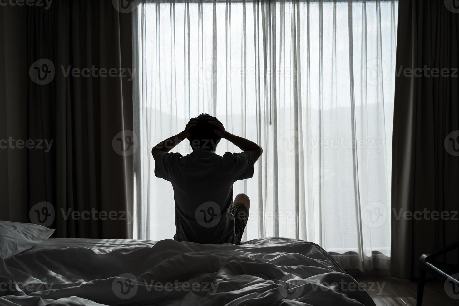 Lonely young man feeling depressed and stressed sitting in the dark bedroom, Negative emotion and mental health concept photo