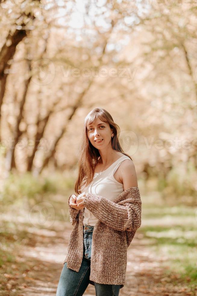 retrato de una chica con cabello castaño, en un cardigan, en un paseo por el bosque. foto