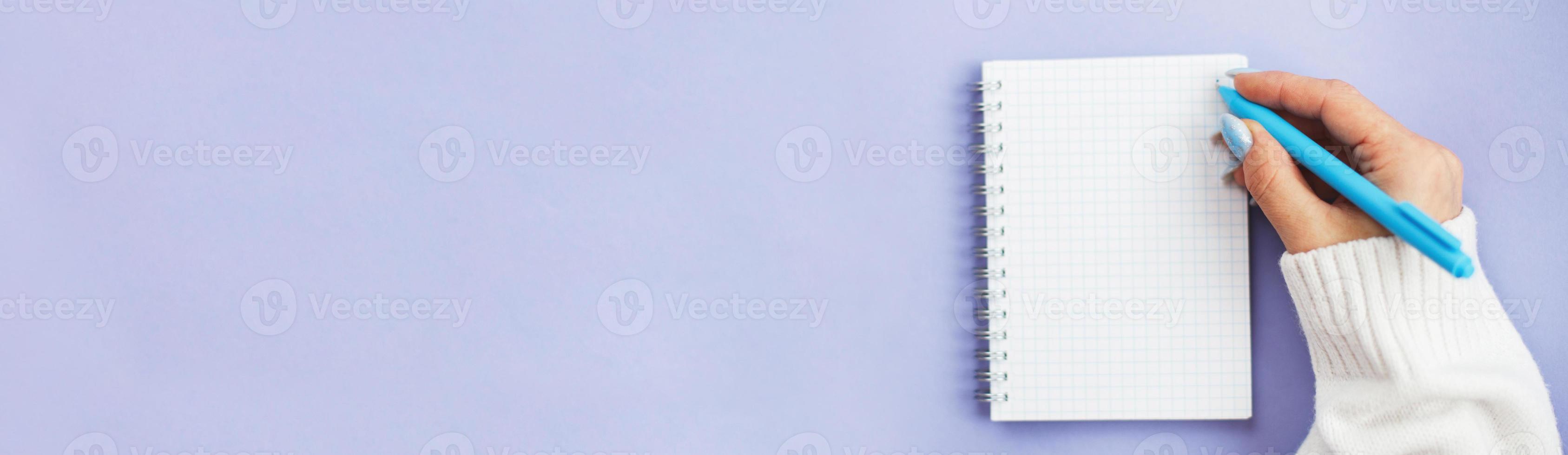 Woman hand with winter nails holding pen on notebook and writing wish list photo