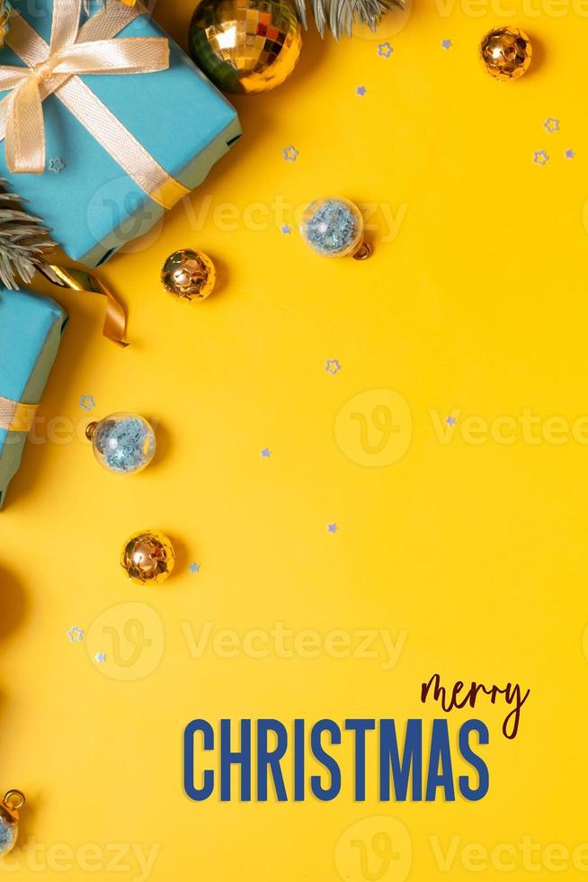 Merry Christmas vertical greeting card with pine tree, gifts and festive decorations top view on colored background photo