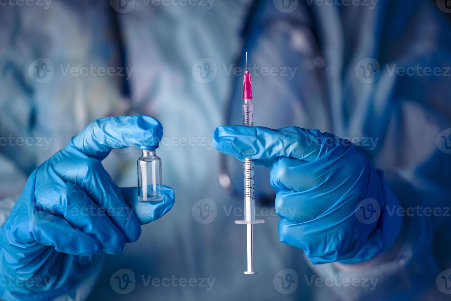 tratamiento de inyección de jeringa de aguja hipodérmica de vacuna de vial azul de guante de mano médica. foto