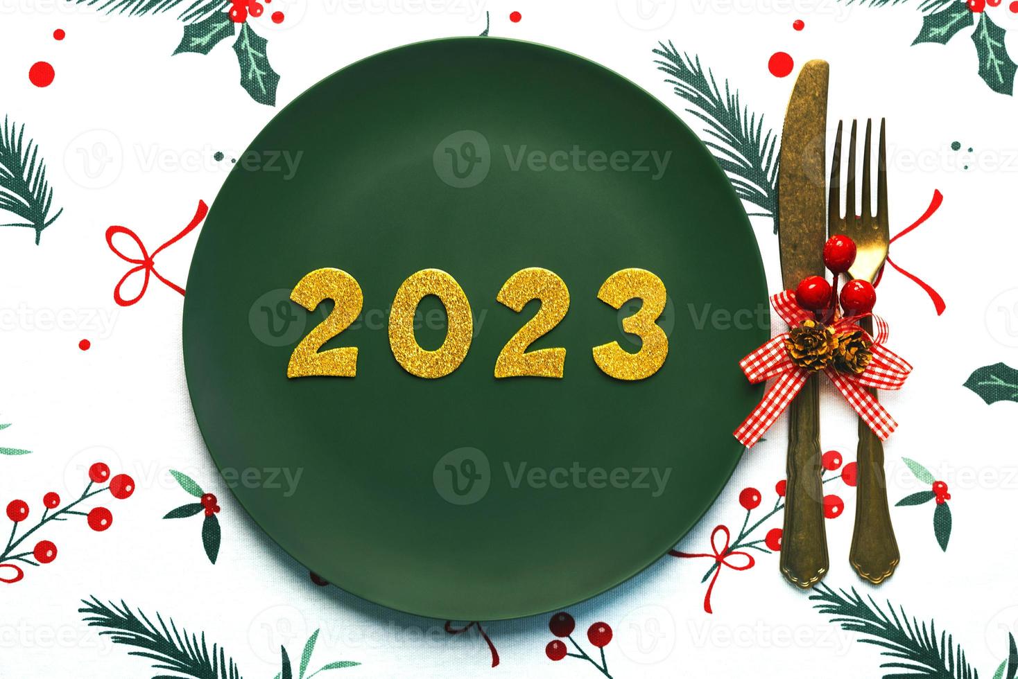 Happy new year 2023. Top view of golden Numbers 2023 on plate with cutlery for Christmas dinner. New Years Eve celebration concept background photo