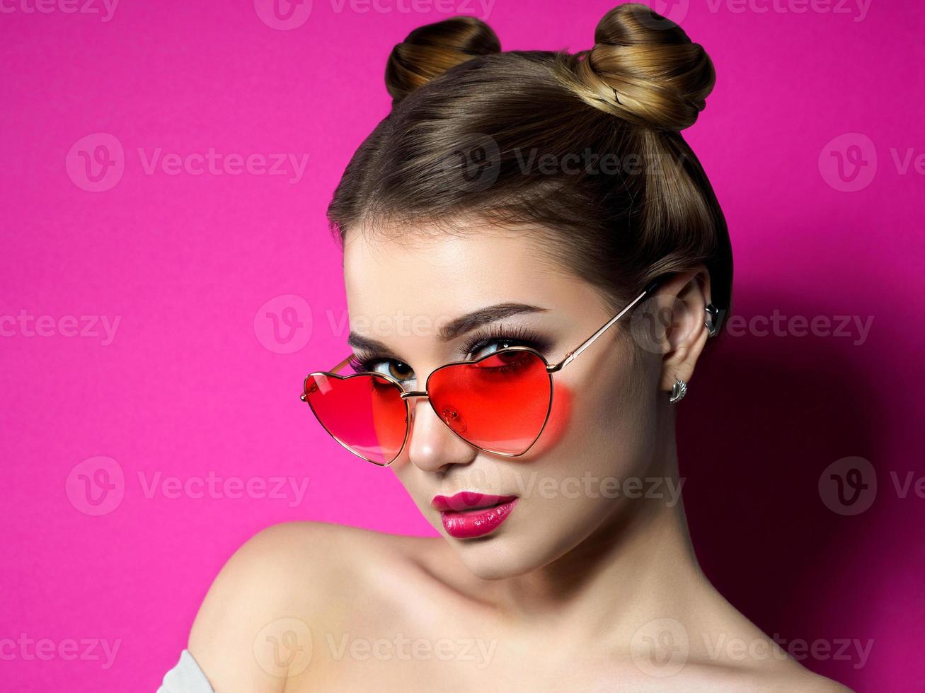 Young woman looks over heart shaped glasses photo