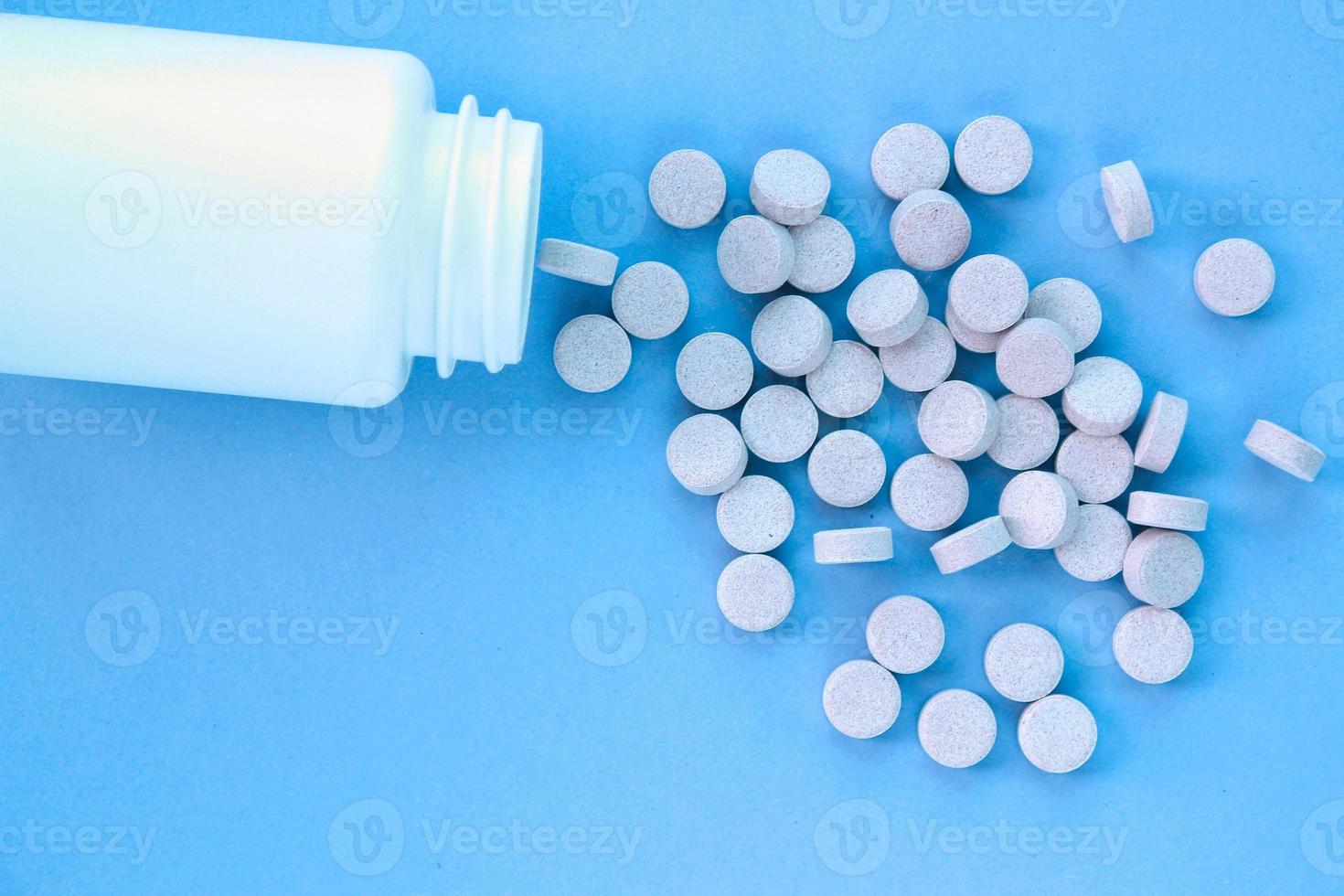 Tablets, capsule, pills and white plastic pack on blue background. Vitamin prescription supplement, drugs, Pharmaceutical medicine health therapy idea. Suicide abuse overdose concept. Doping steroid photo