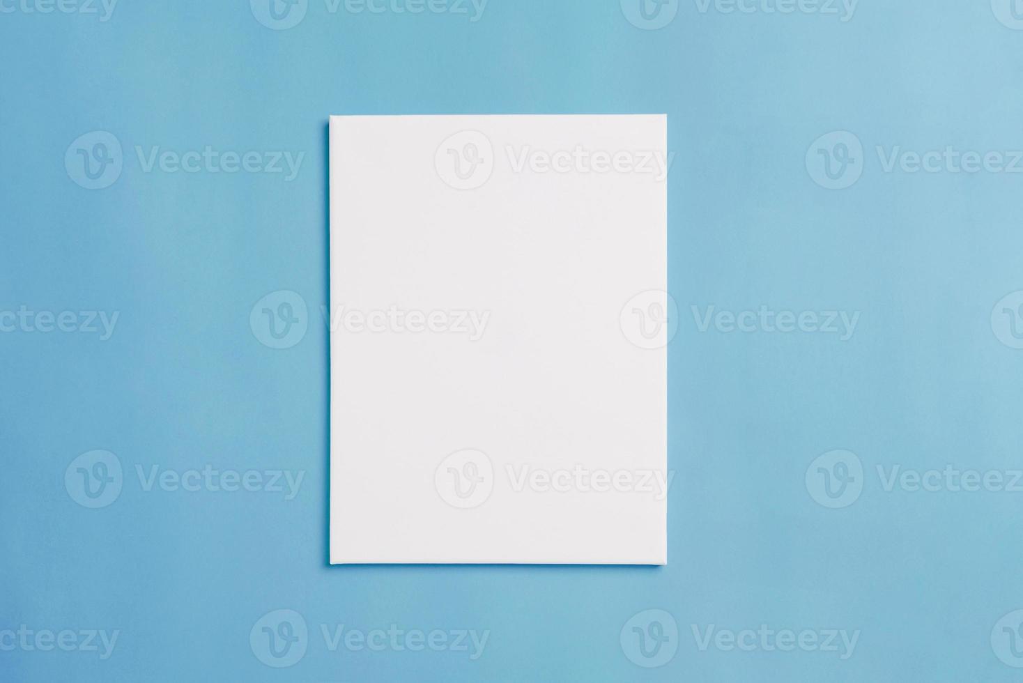 Empty white canvas on blue floor for painting presentation. Top view, flat lay photo
