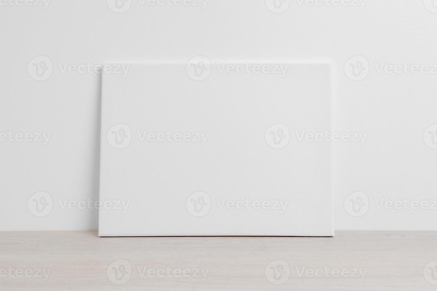 Art canvas in a horizontal position on the floor leaning against a white wall. Clean cloth for mockup art presentation photo