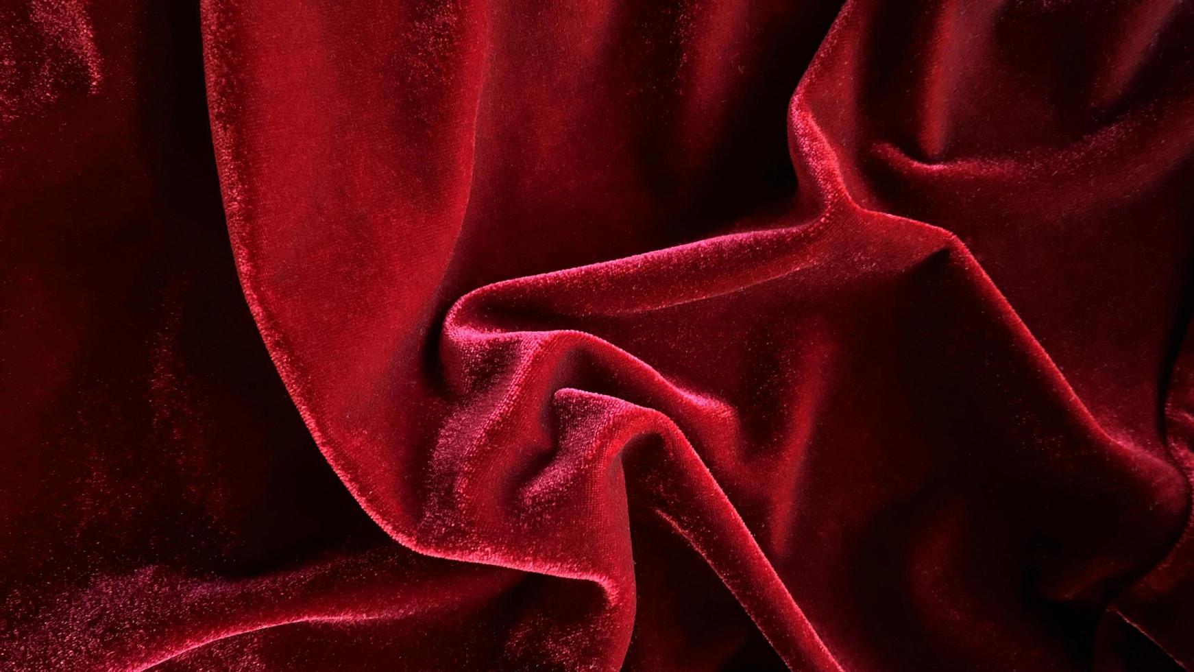 textura de tela de terciopelo rojo utilizada como fondo. fondo de tela roja vacía de material textil suave y liso. hay espacio para el texto. foto