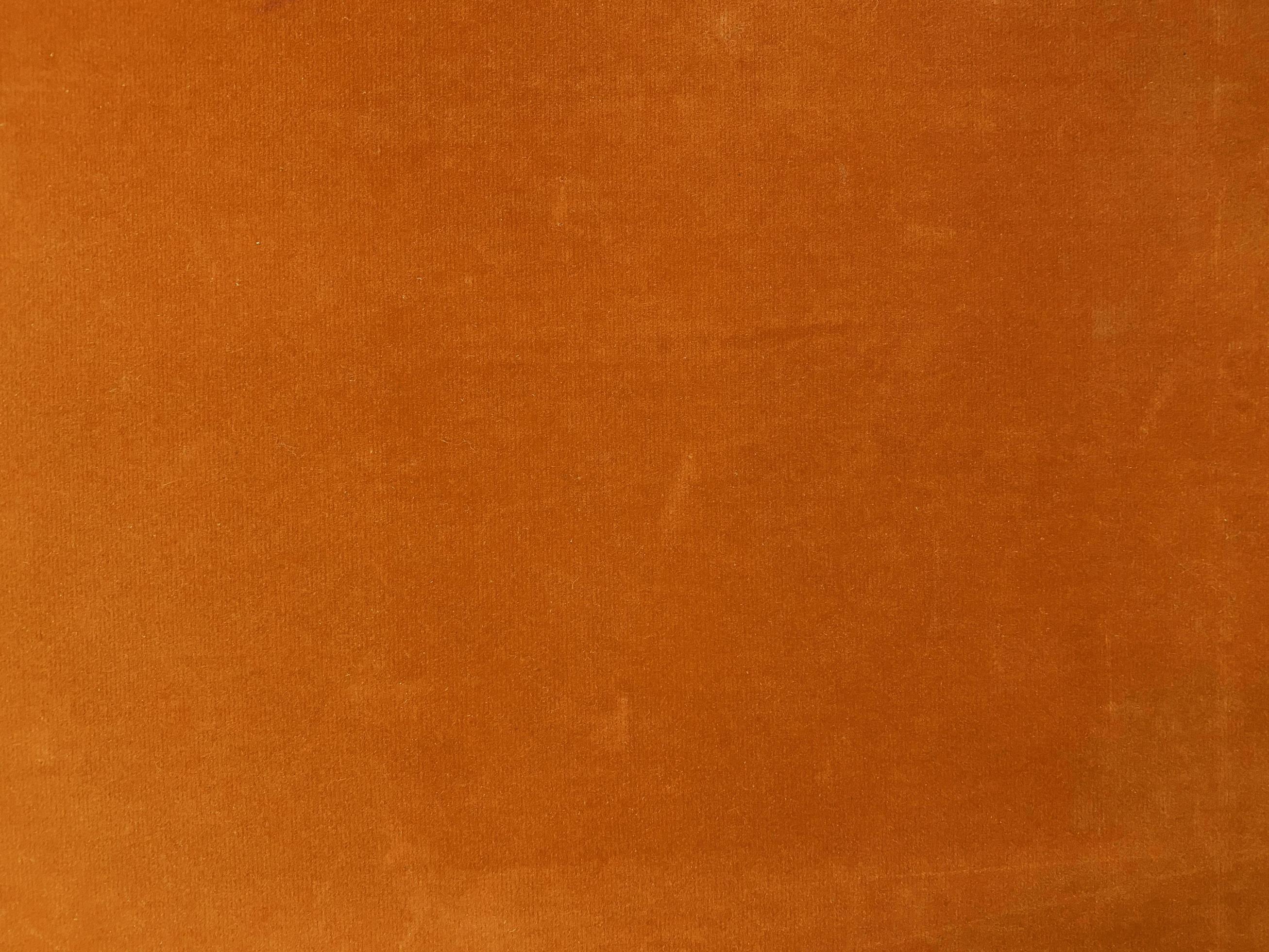 Orange velvet fabric texture used as background. Empty orange fabric