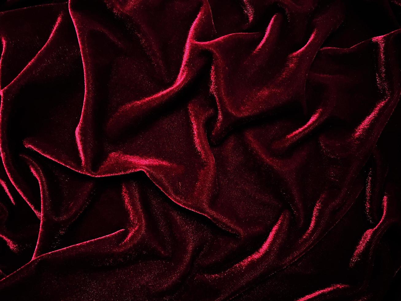 textura de tela de terciopelo rojo utilizada como fondo. fondo de tela roja vacía de material textil suave y liso. hay espacio para el texto. foto