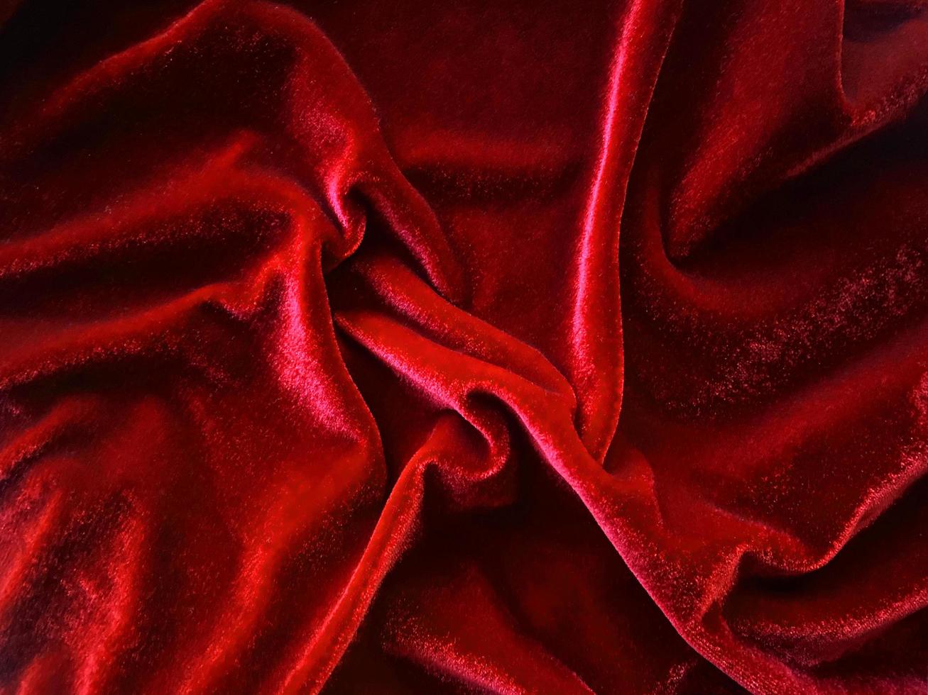 textura de tela de terciopelo rojo utilizada como fondo. fondo de tela roja vacía de material textil suave y liso. hay espacio para el texto. foto