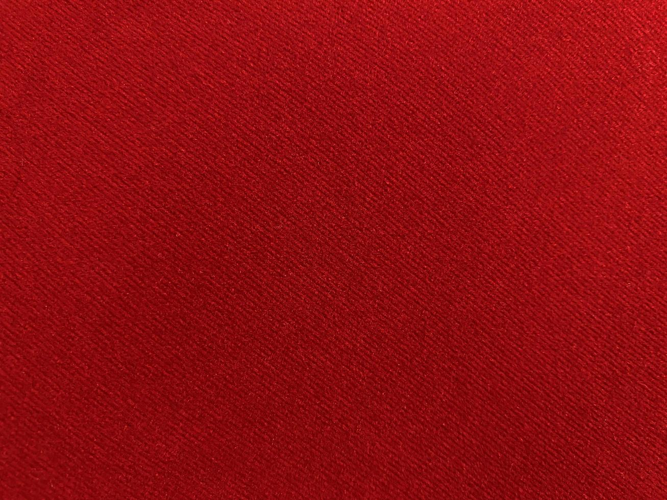 textura de tela de terciopelo rojo utilizada como fondo. fondo de tela roja vacía de material textil suave y liso. hay espacio para el texto. foto