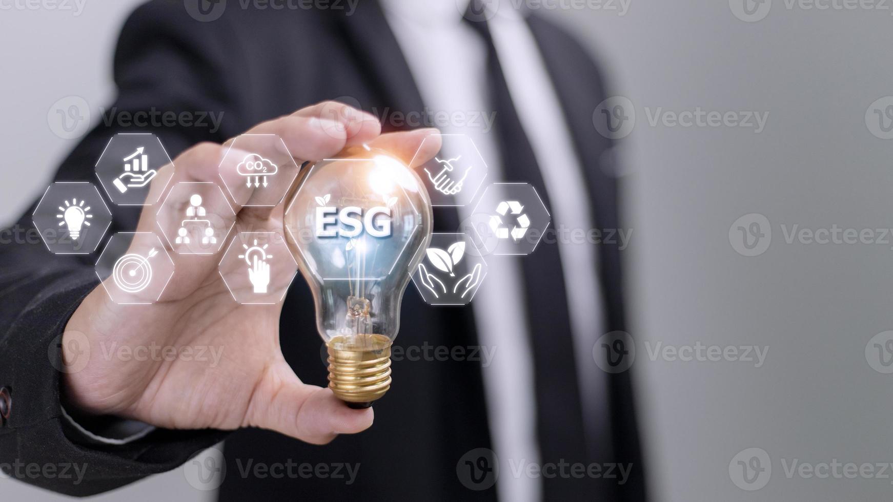 Businessman hand holding light bulb with esg icon on virtual screen, ESG Environmental, social and corporate governance concept photo