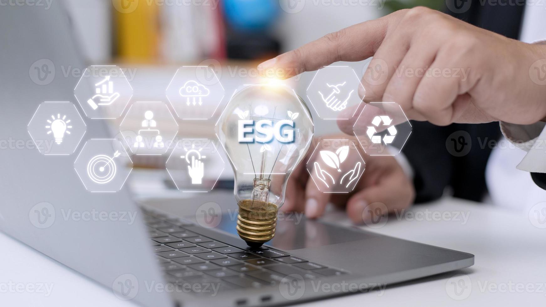 mano de hombre de negocios sosteniendo una bombilla con un icono de esg en la pantalla virtual, esg concepto ambiental, social y de gobierno corporativo foto