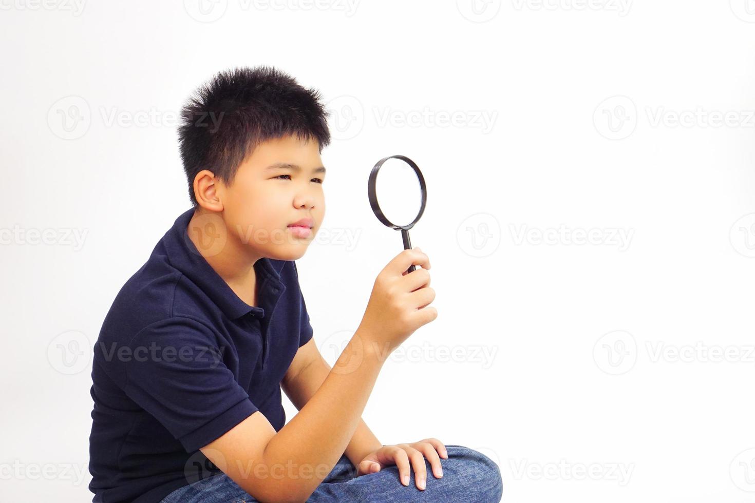 Boy holding a magnifying glass on white background. Knowledge, research and explore concept. photo