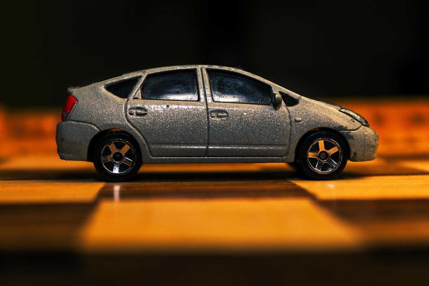 A gray automobile toy with various unique patterns on it is shown on a chessboard. photo