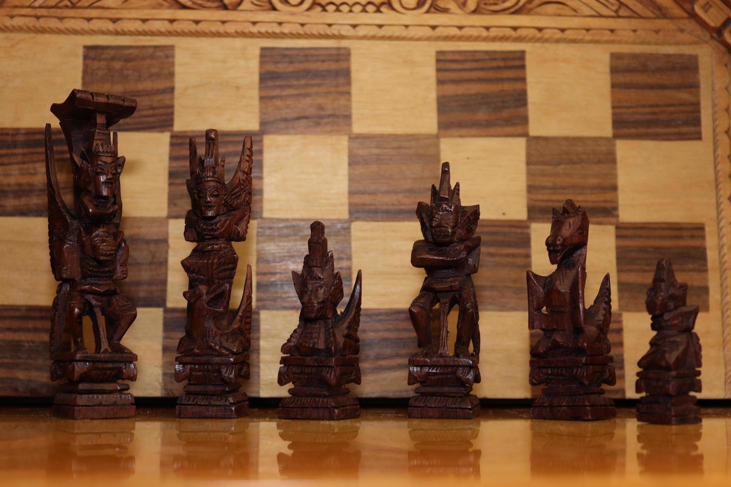 Mayan chess pieces photographed on a background showing a chess board photo