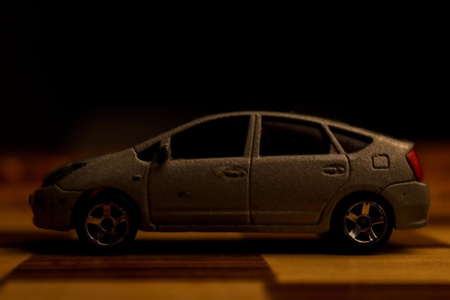 A gray automobile toy with various unique patterns on it is shown on a chessboard. photo