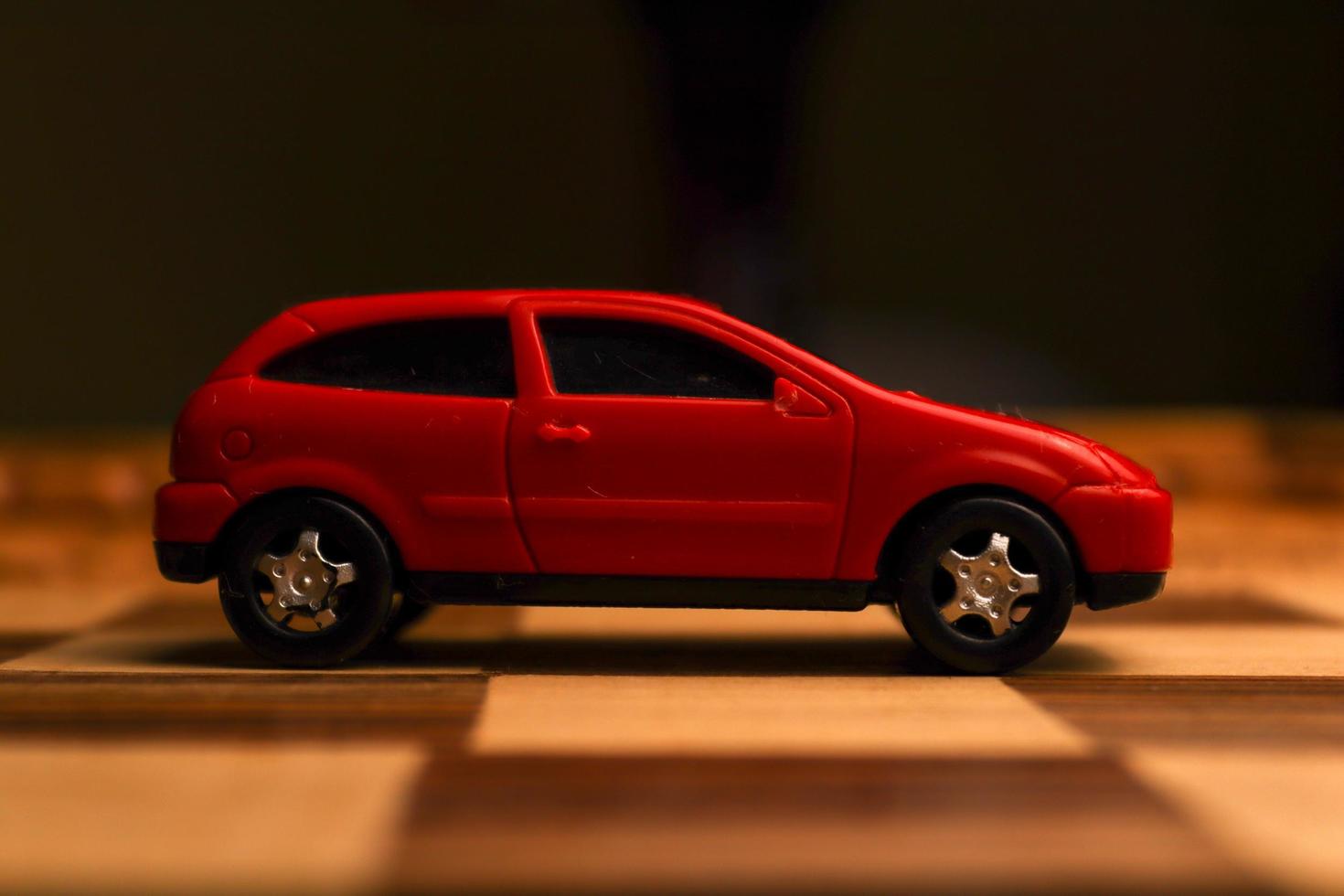 Red vehicle toy on a chessboard with various unique patterns drawn on it photo