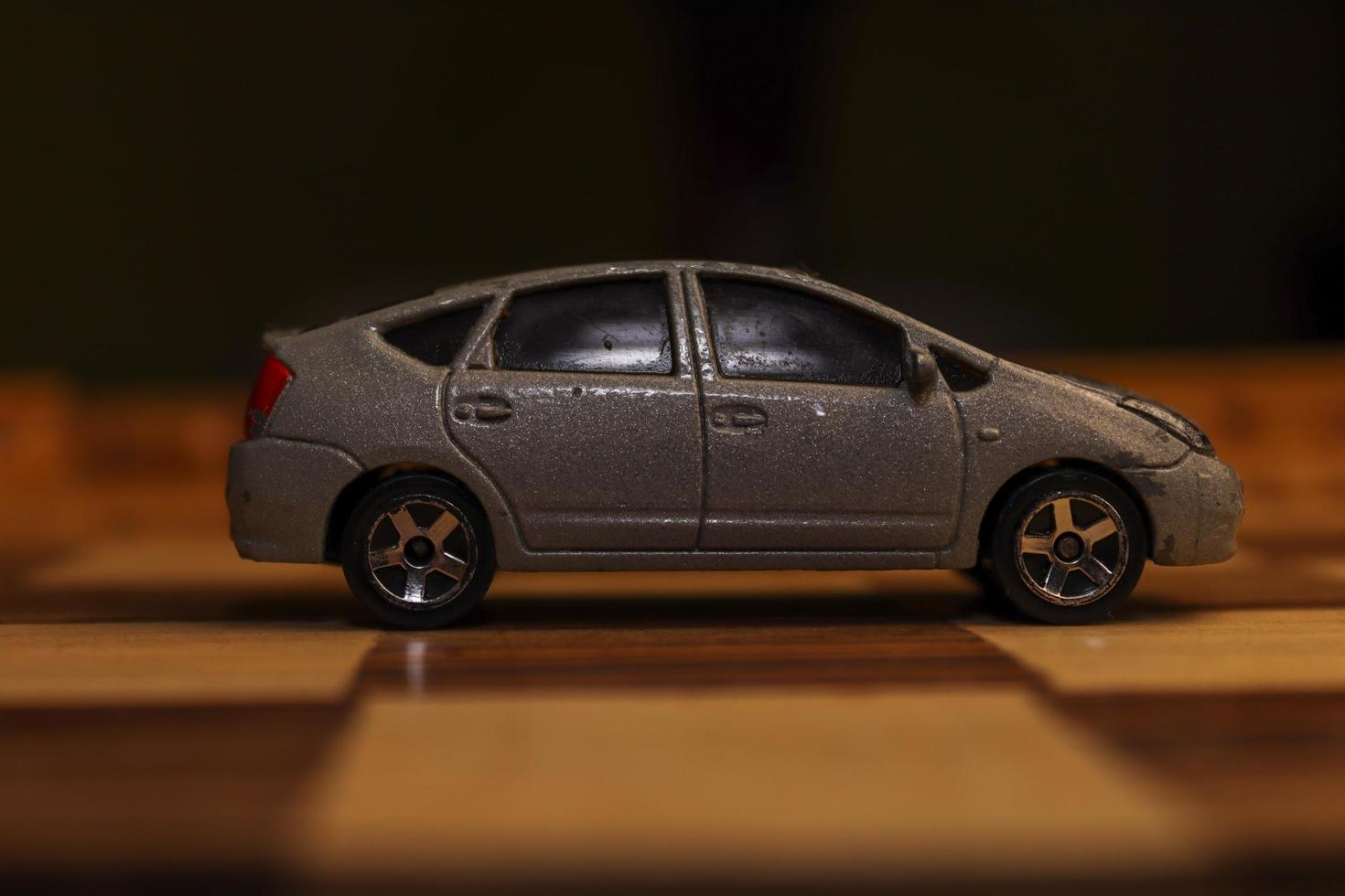 A gray automobile toy with various unique patterns on it is shown on a chessboard. photo