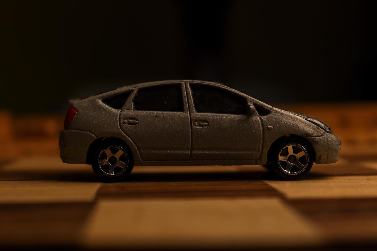 A gray automobile toy with various unique patterns on it is shown on a chessboard. photo