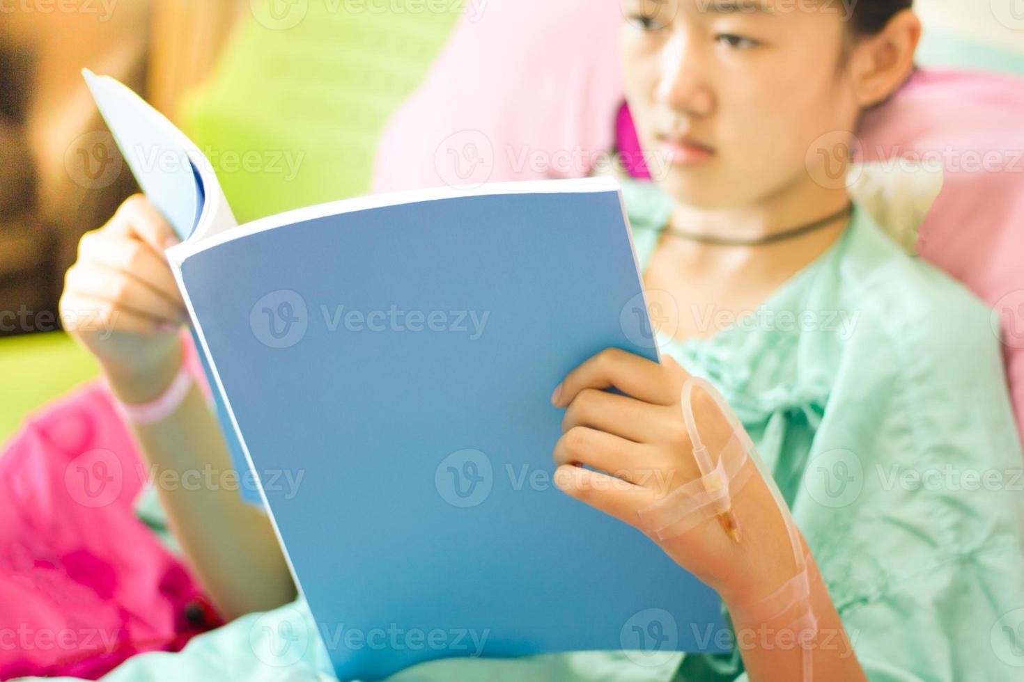 Saline drip in patient's hand while reading on the bed photo