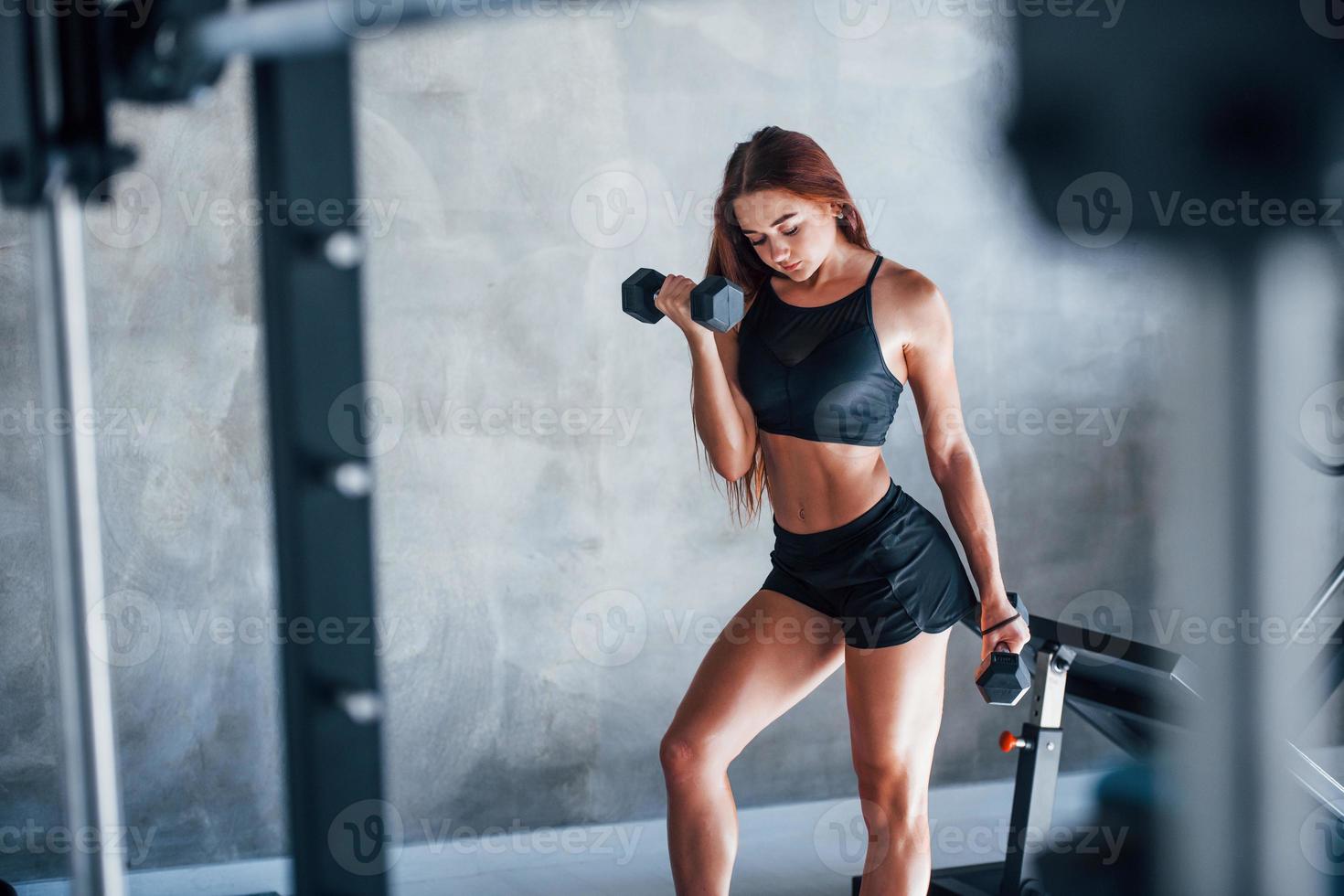 mujer joven fitness está en el gimnasio con pesas en las manos foto