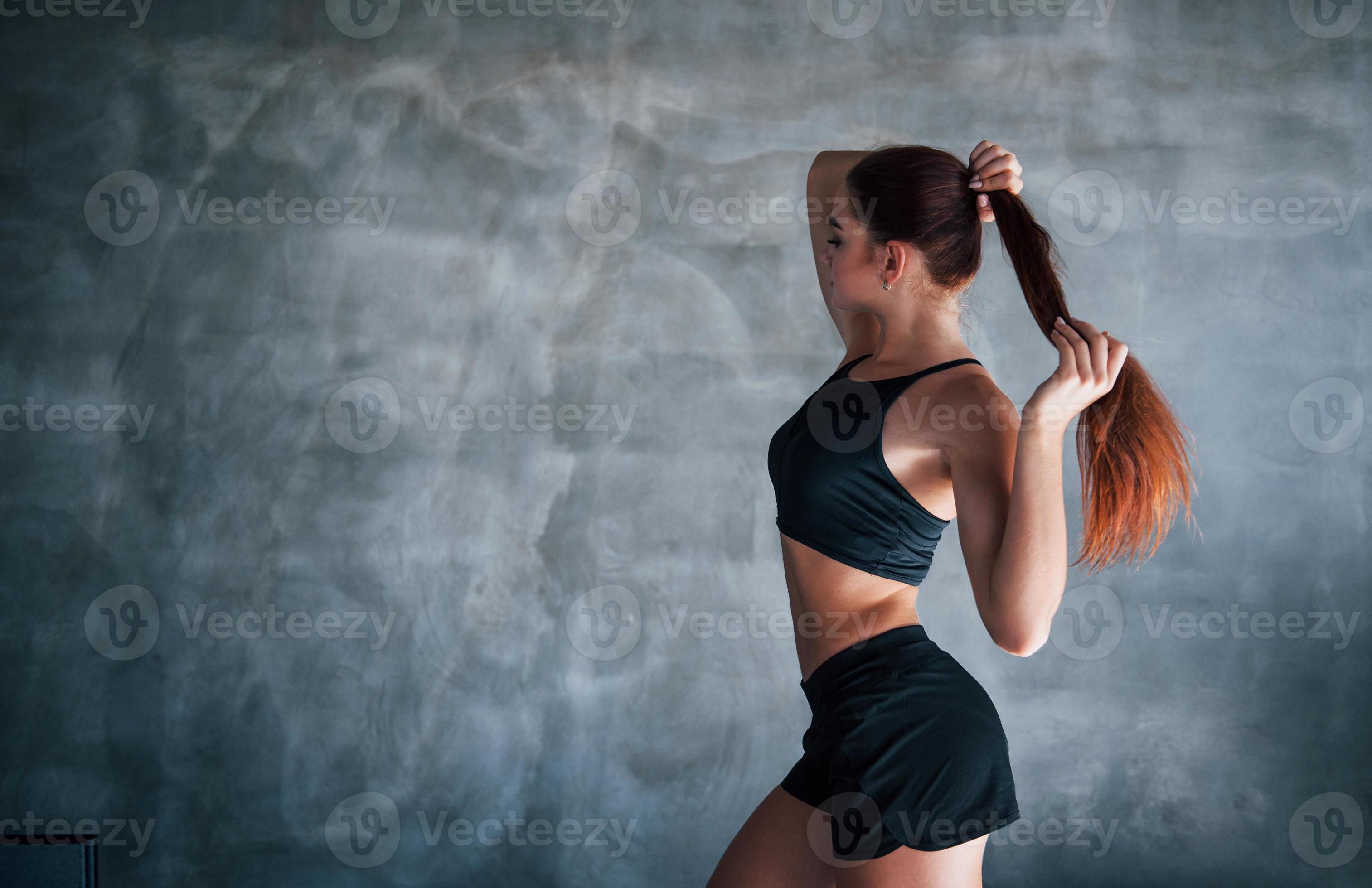 Mujer joven fitness con cuerpo delgado y ropa deportiva negra está en el  gimnasio.