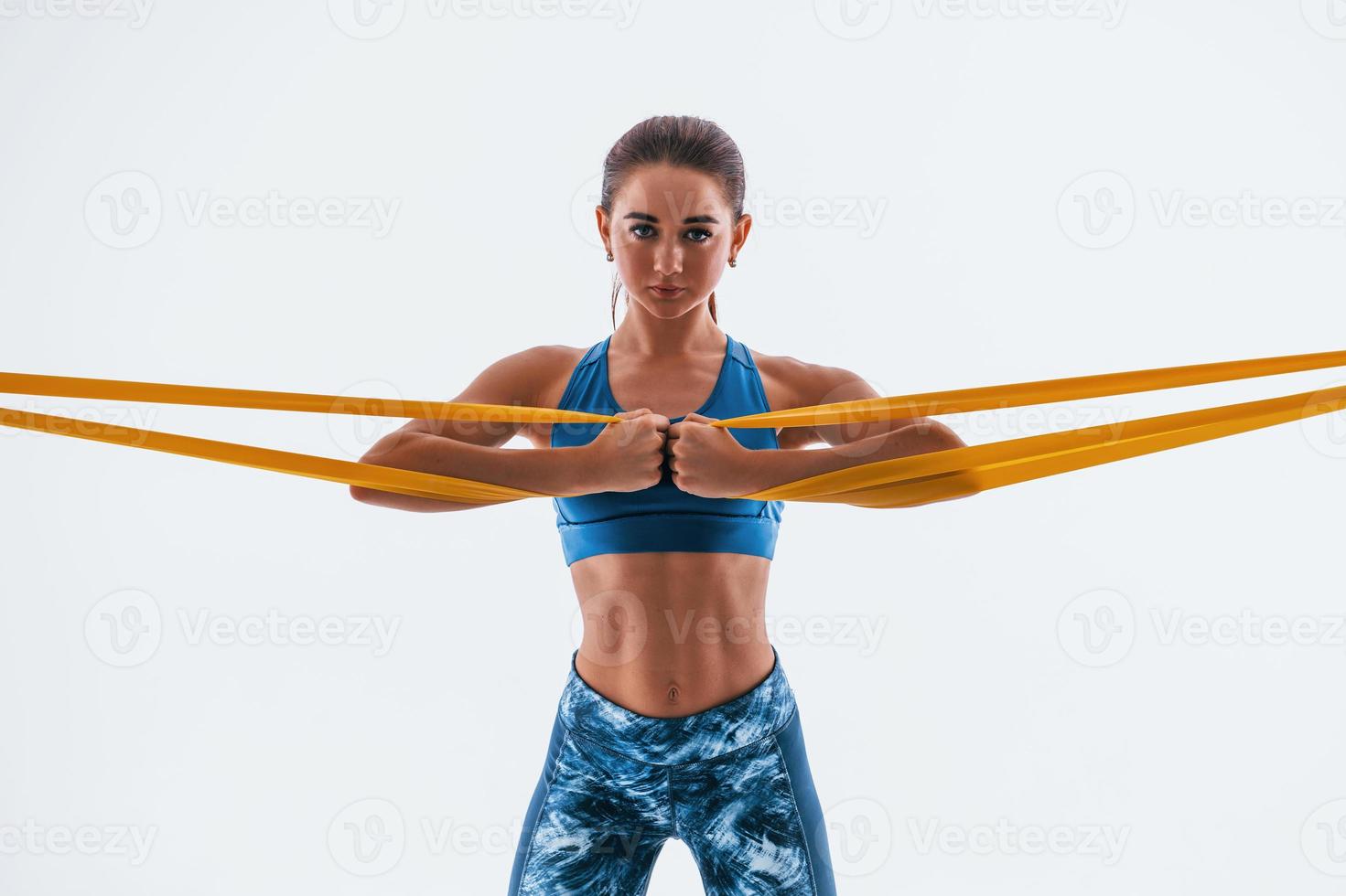 With yellow resistance band. Young woman with slim body type isolated against white background photo