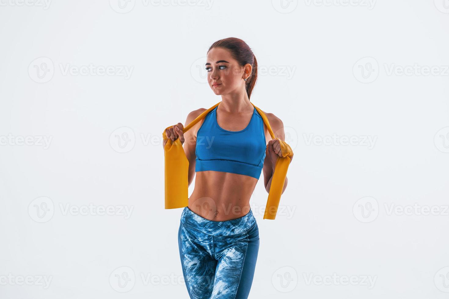 With yellow resistance band. Young woman with slim body type isolated against white background photo