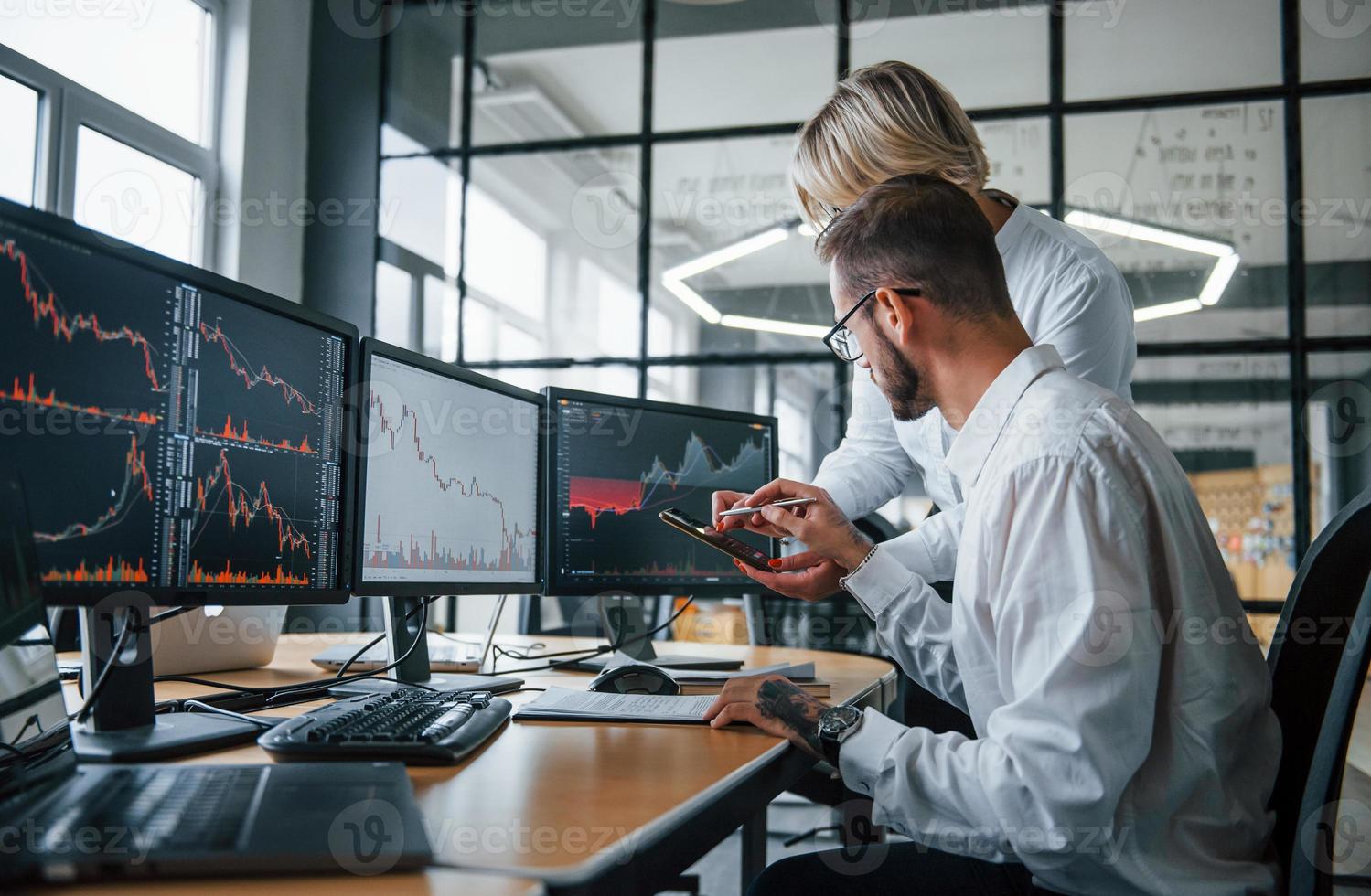 dos corredores de bolsa con ropa formal trabajan en la oficina con el mercado financiero foto