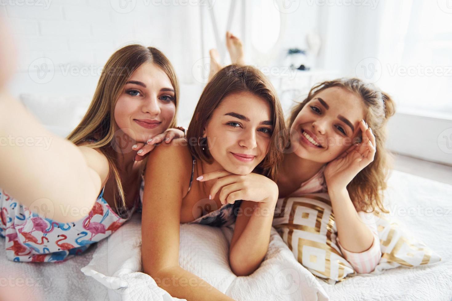 haciendo selfie amigas felices pasando un buen rato en la fiesta de pijamas en el dormitorio foto