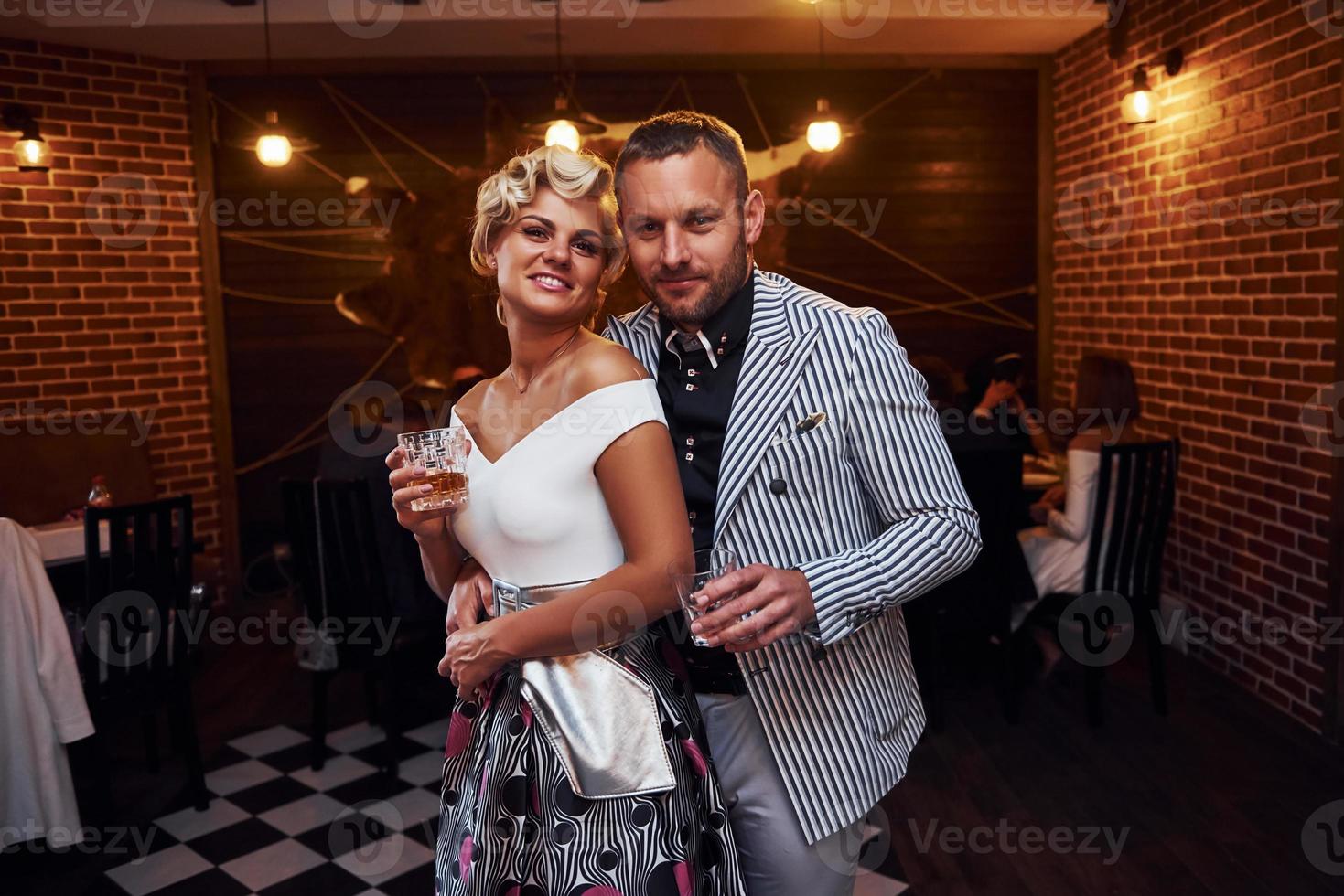 Couple with glasses of alcohol in hands stands in the restaurant photo