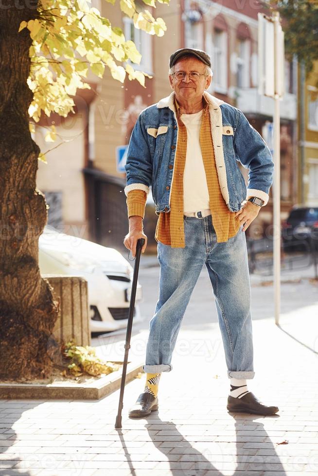 Stylish senior in fashionable clothes and in glasses have a walk in the city photo