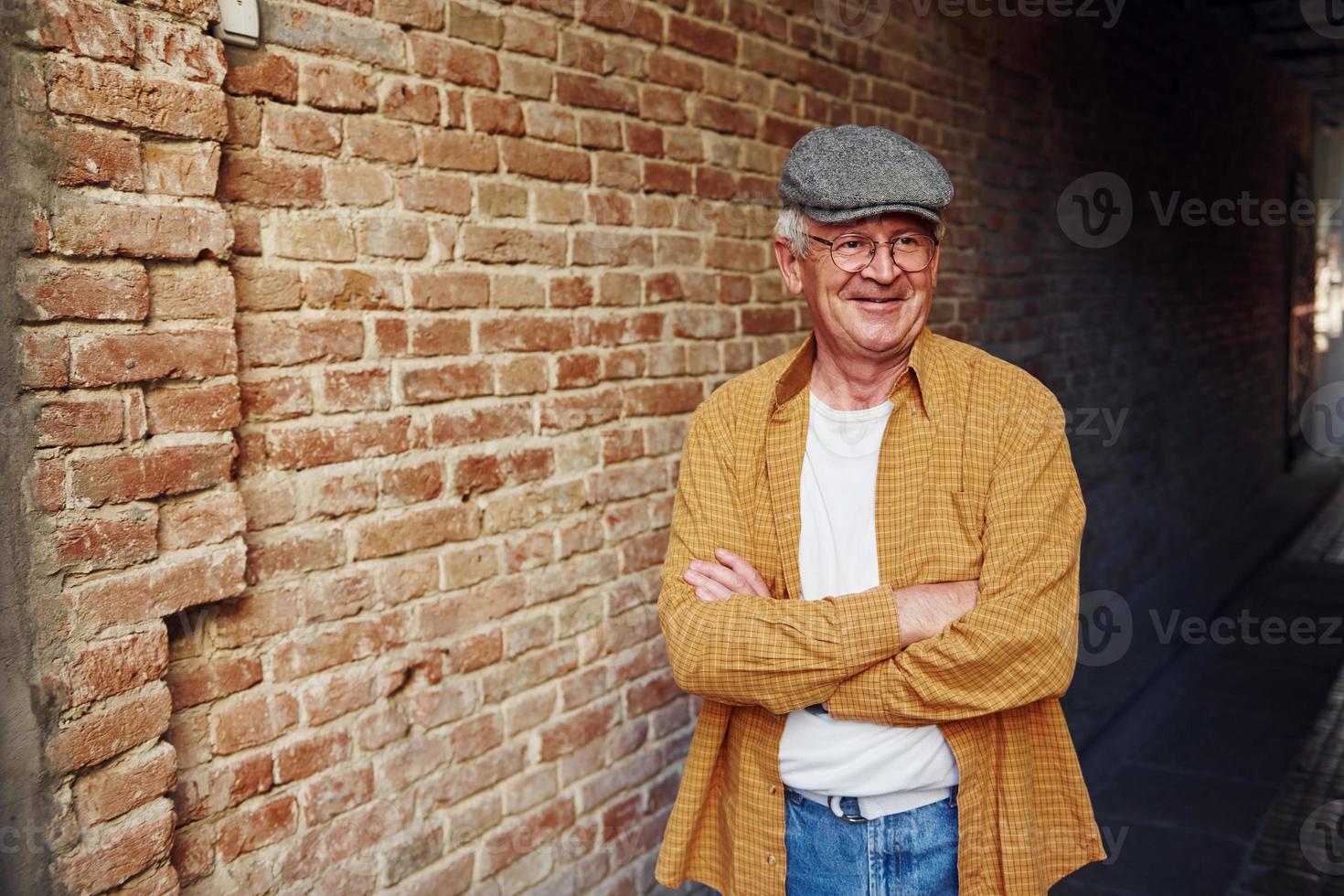 senior con estilo en ropa de moda y en soportes de gafas con los brazos cruzados foto