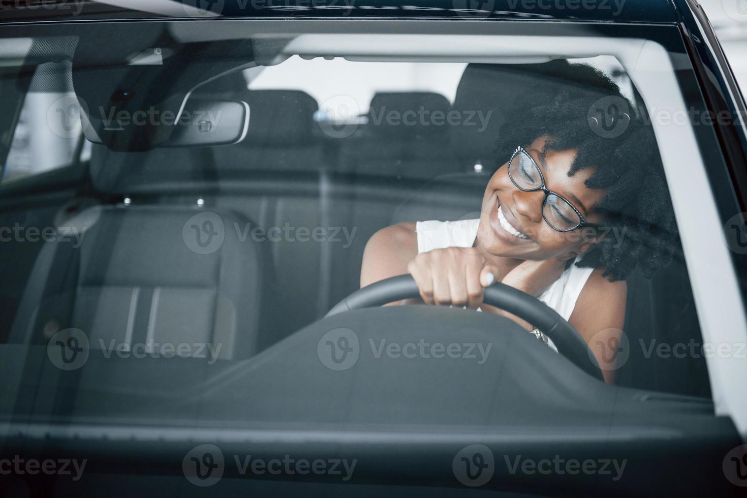 una joven afroamericana se sienta dentro de un auto nuevo y moderno foto