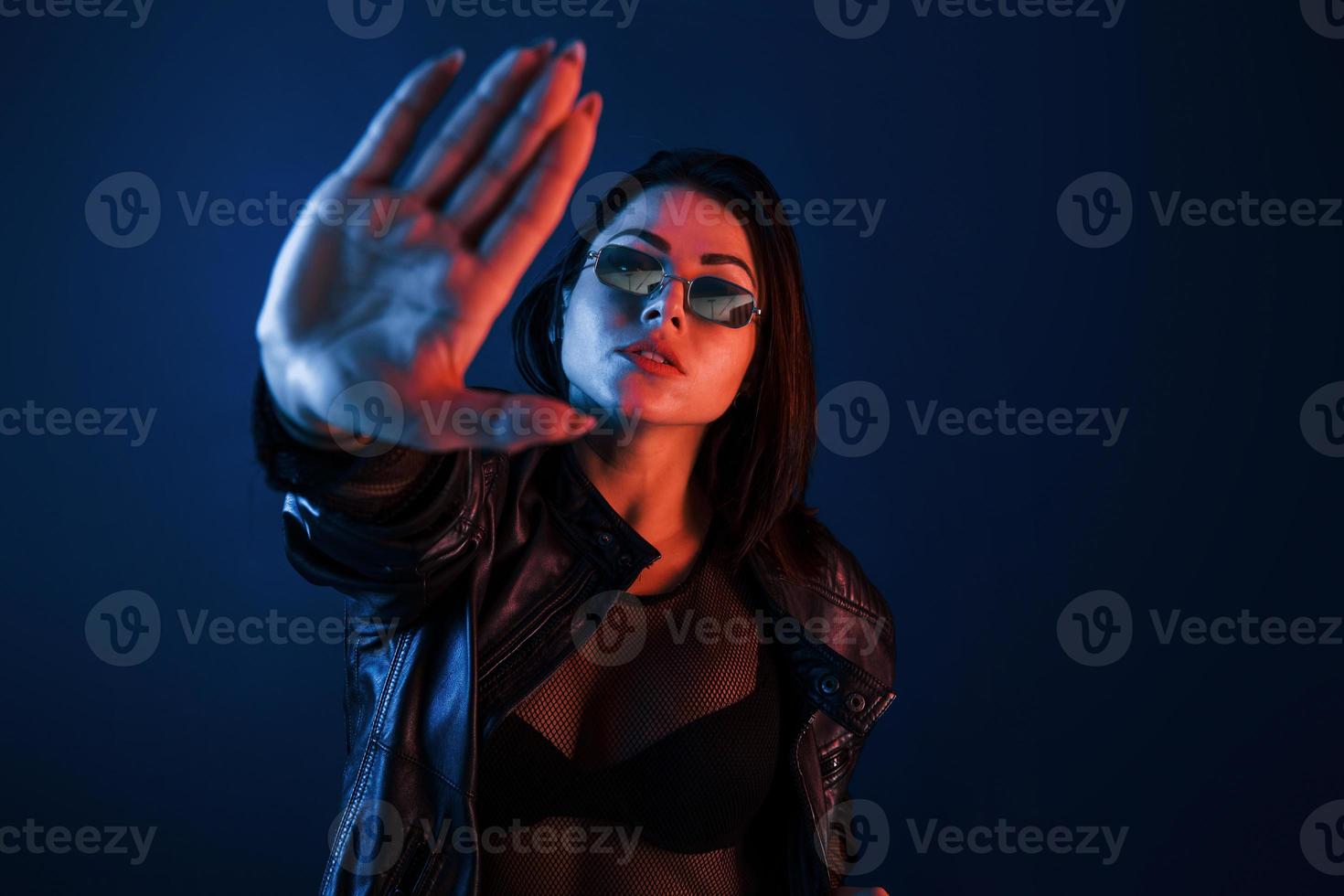 Hot brunette in sunglasses posing in the studio with neon lighting photo