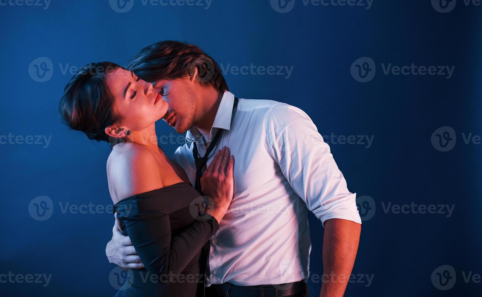 Beautiful man with his hot girlfriend is in the studio with blue neon lighting. Couple in love with each other photo