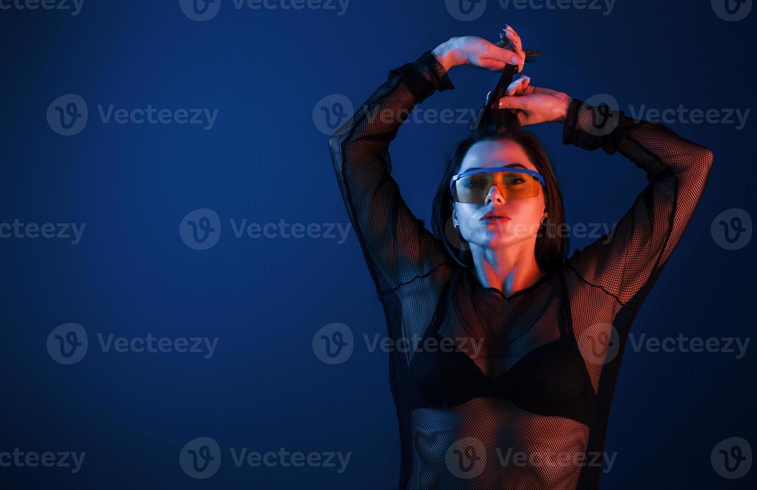 Hot brunette in sunglasses posing in the studio with neon lighting photo