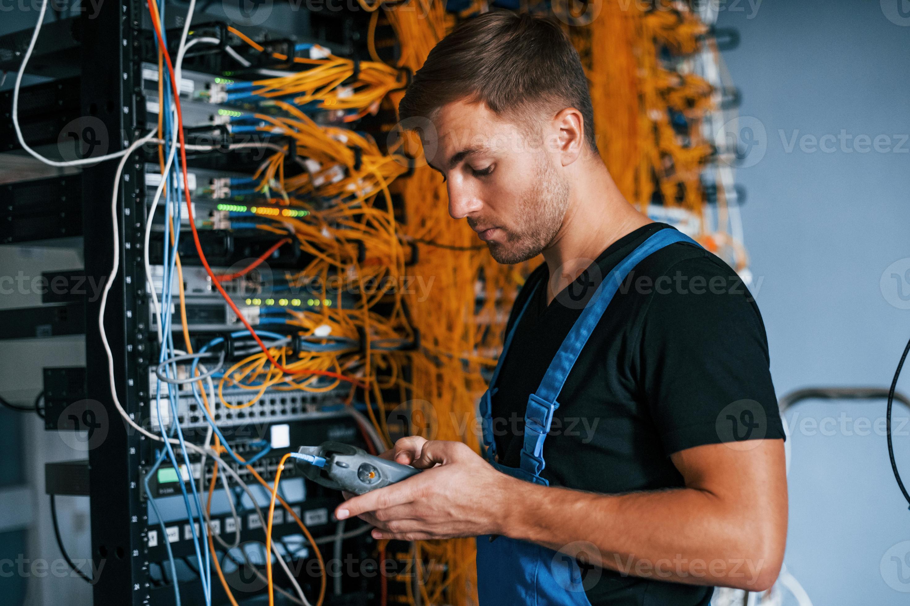 Young Man In Uniform Have A Job With Internet Equipment And Wires In young-man-in-uniform-have-a-job-with-internet-equipment-and-wires-in