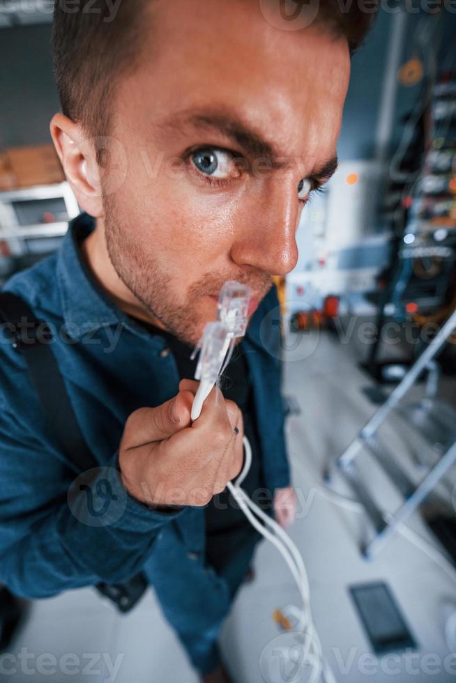 Close up view of funny man with internet wires in server room photo